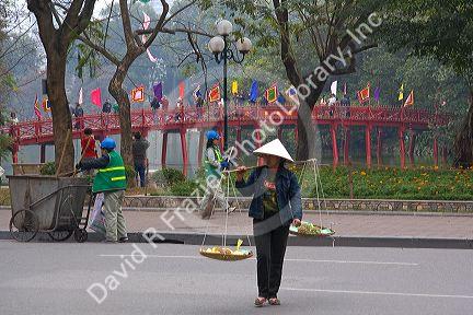 Street vendor in front of the Huc Bridge on Hoan Kiem Lake in Hanoi, Vietnam.