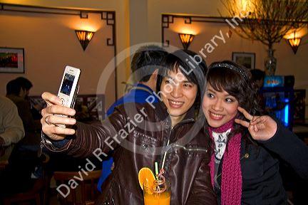 Young Vietnamese couple taking a cell phone photo of themselves during Tet festivities in Hanoi, Vietnam.