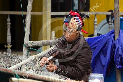 Vietnamese man repairing fishing nets in Ha Long Bay, Vietnam.
