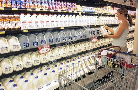 Woman shopping for milk in a grocery store.