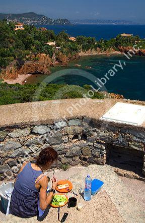 Woman having a picnic lunch overlooking the Mediterranean Sea near Frejus in Southern France.