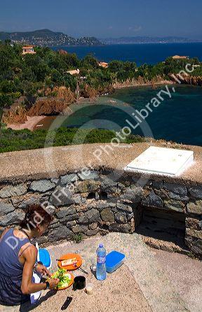 Woman having a picnic lunch overlooking the Mediterranean Sea near Frejus in Southern France.