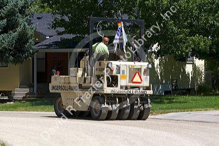 Rubber tire roller compacting chip seal pavement resurfacing treatment on a residential street in Boise, Idaho, USA.