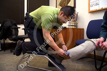 Law enforcement agent attaching an ankle monitor to a criminal under house arrest.