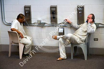 Inmates talk on telephones in the day use area of a county jail.