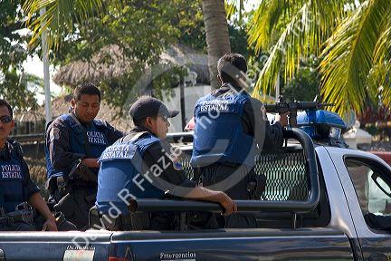 Mexican police with guns sit in the back of a police truck in Acapulco, Guerrero, Mexico.