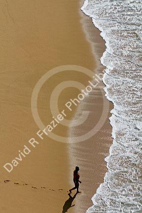 Man walking on the beach into the surf at Acapulco, Guerrero, Mexico.