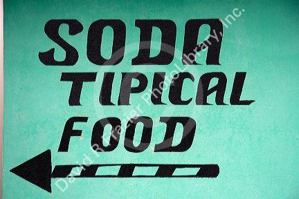 Spanish language sign directing to a small restaurant called a soda near the town of Nuevo Arenal, Costa Rica.