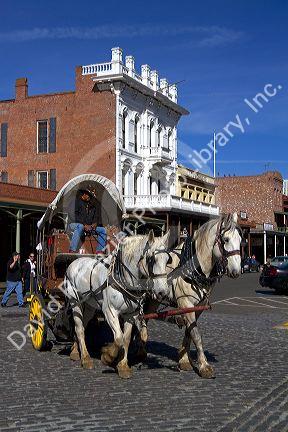 Tourists ride in a horse drawn covered wagon at Old Sacramento State Historic Park in Sacramento, Califorina, USA.