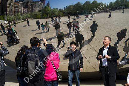 Visitors look at their reflection in the Cloud Gate public sculpture located at the AT&T Plaza in Millennium Park, Chicago, Illinois.
