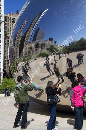 Visitors look at their reflection in the Cloud Gate public sculpture located at the AT&T Plaza in Millennium Park, Chicago, Illinois.
