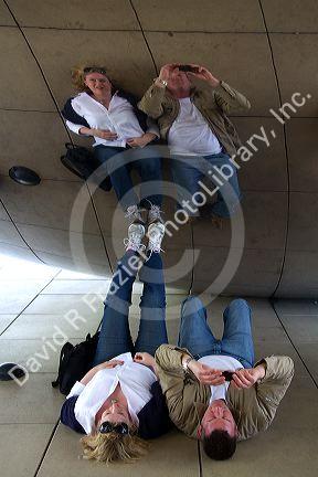 Visitors look at their reflection in the Cloud Gate public sculpture located at the AT&T Plaza in Millennium Park, Chicago, Illinois.