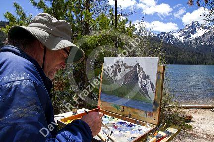 Artist painting McGown Peak and Stanley Lake in the Sawtooth Mountain Range near Stanley, Idaho, USA.