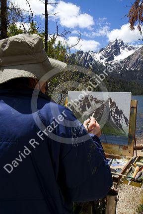 Artist painting McGown Peak and Stanley Lake in the Sawtooth Mountain Range near Stanley, Idaho, USA.