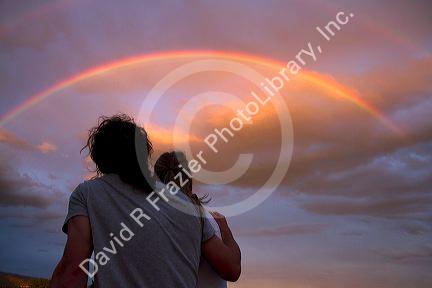 A couple viewing a rainbow at sunset in Boise, Idaho, USA.