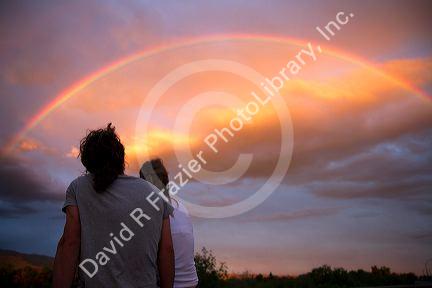A couple viewing a rainbow at sunset in Boise, Idaho, USA.