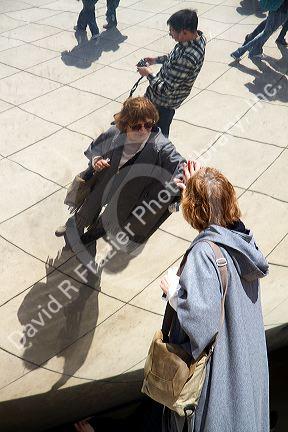 Visitors look at their reflection in the Cloud Gate public sculpture located at the AT&T Plaza in Millennium Park, Chicago, Illinois.