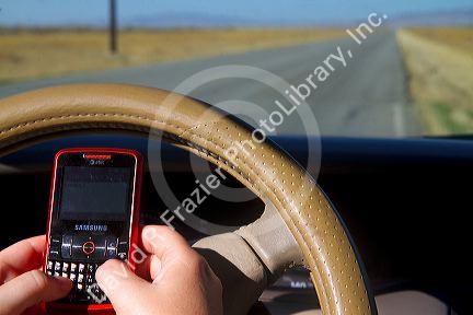 Text messaging on a cell phone while driving in Idaho, USA. MR
