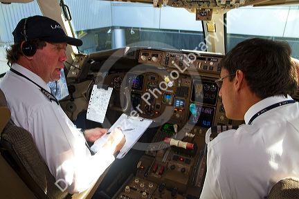 Pilot and first officer reviewing a pre-flight checklist in the cockpit of a Boeing 767 aircraft.