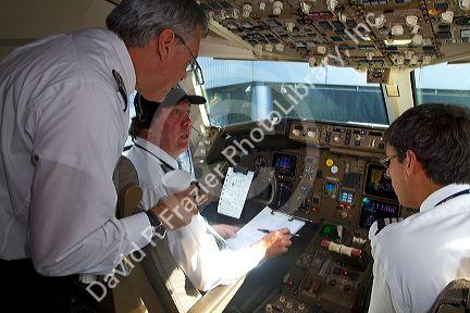 Pilot and first officer reviewing a pre-flight checklist in the cockpit of a Boeing 767 aircraft.