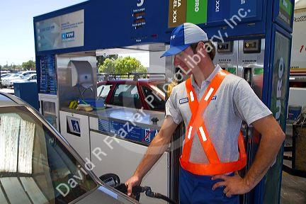 Gas station attendent fueling an automobile in Argentina.
