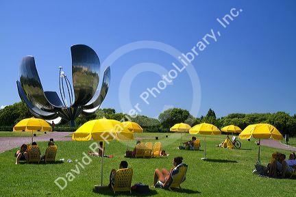 People sit under yellow umbrellas near the Floralis Generica sculpture located in Plaza de las Naciones Unidas in Buenos Aires, Argentina.