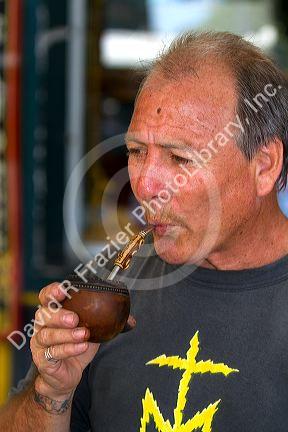 Man drinking mate out of a traditional hollow gourd with a metal straw in Buenos Aires, Argentina.
