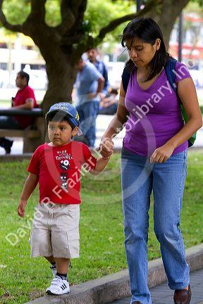 Mother and son holding hands in Central Park of the Miraflores district of Lima, Peru.