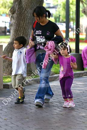 Mother holding hands with two children in Central Park of the Miraflores district of Lima, Peru.