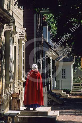 Woman wearing a red cape in front of a shop in colonial Williamsburg, Virginia.