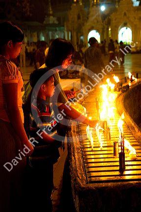 A young boy lighting a candle at the Shwedagon Paya located in (Rangoon)Yangon, (Burma) Myanmar.