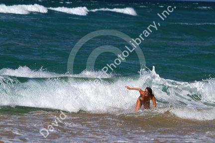 Woman in the pacific ocean at Polihale Beach and State Park located on the western side of the island of Kauai, Hawaii, USA.