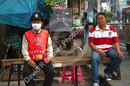 Thai police officer wearing a protective filtering mask to avoid breathing car exhaust fumes in Bangkok, Thailand.