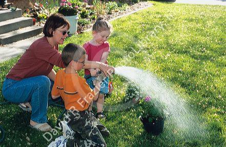 Adult and children watering flowers in the yard.