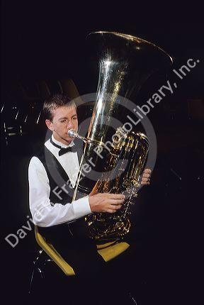 A teen playing an upright tuba.