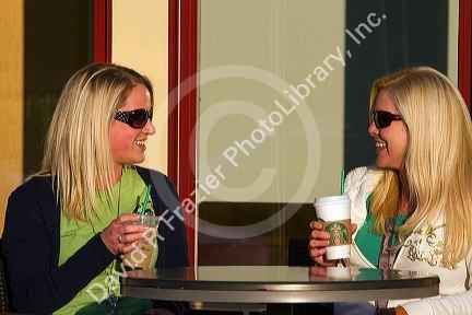 Two female friends having coffee at an outdoor cafe in Tampa, Florida, USA. MR