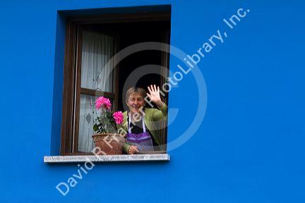 Spanish woman waves hello from the window of her home in the municipality of Cangas de Onis in Asturias, Spain. MR