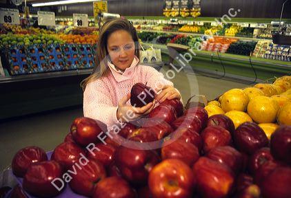 A young woman shopping for fruits and vegetables in a supermarket.