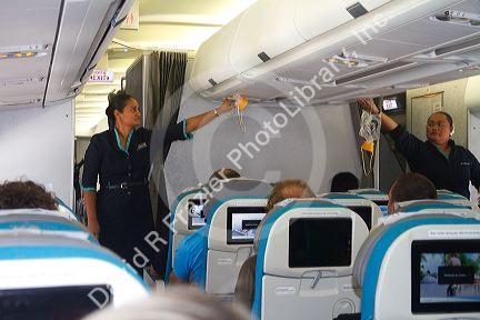 Passengers seated in an Airbus 340 with flight attendant giving safety instruction at the Auckland Airport, Auckland, North Island, New Zealand.
