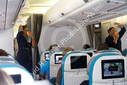 Passengers seated in an Airbus 340 with flight attendant giving safety instruction at the Auckland Airport, Auckland, North Island, New Zealand.