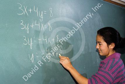 A junior high student works an algebra problem on the black board.