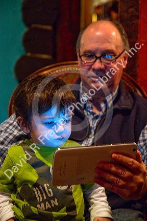 Man reading from an iPad tablet to a young boy in Boise, Idaho, USA.