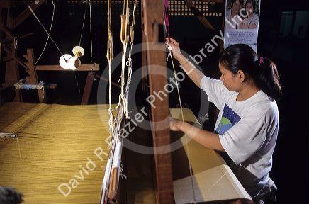 A thai woman weaves silk cloth on loom at Chiang Mai Thailand.
