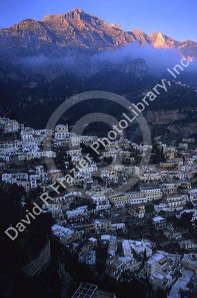 Sun hits the mountain peaks behind Positano, Italy along the Amalfi Coast.