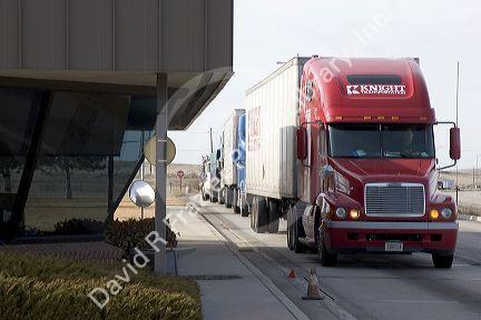 Long haul trucks line up a weigh station.