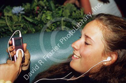 A sixteen year old female teenager listening to an iPod mini mp3 player.