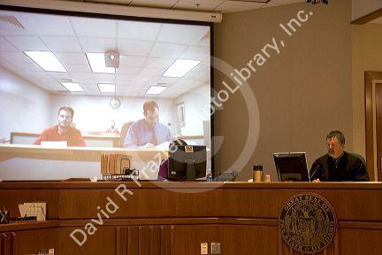 Video arraignment in criminal court in Boise, Idaho.  Defendants appear on video screen from secure jail facility while judge in courtroom conducts arraignment and sets bond.