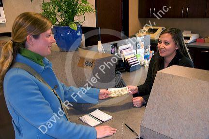 Customer depositing cash at a teller window.