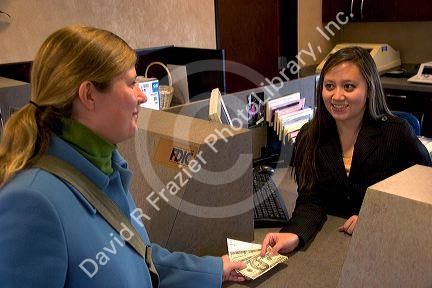 Customer depositing cash at a teller window.