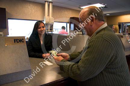 Customer depositing cash at a teller window.